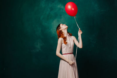 Low section of woman with balloons against blue background