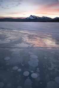 Scenic view of frozen lake against sky during sunset