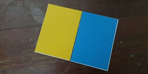 High angle view of yellow paper on table against wall