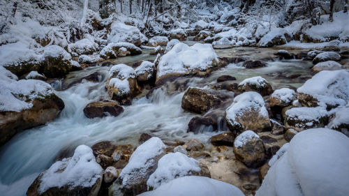 Stream flowing through rocks during winter