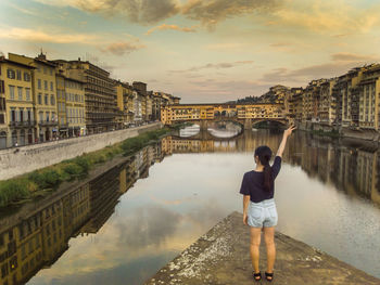 Woman standing by river against sky