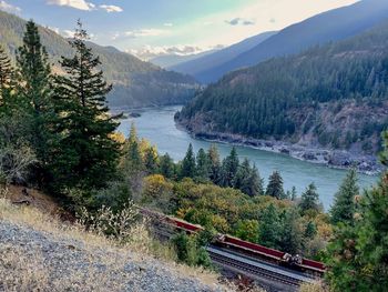 Scenic view of lake and mountains against sky with train