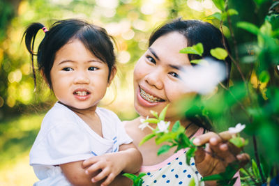 Portrait of happy mother with daughter by plants