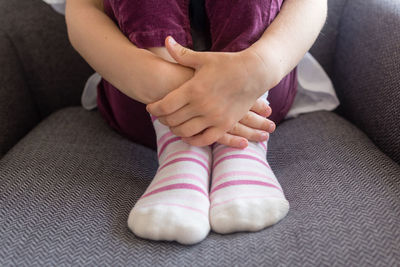 Low section of woman sitting on sofa at home