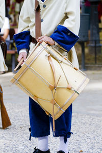 Midsection of man playing drum while standing on road in city