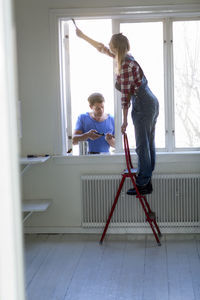Young couple painting windows, stockholm, sweden