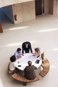 Business colleagues discussing over document on table in corridor