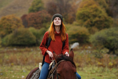 Young woman wearing hat while sitting on land