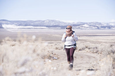 Full length of female hiker exploring desert against sky during winter