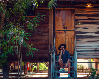 Portrait of man sitting on wooden door