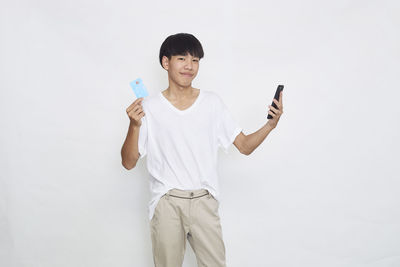 Full length portrait of smiling man standing against white background