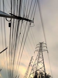 Low angle view of silhouette electricity pylon against sky