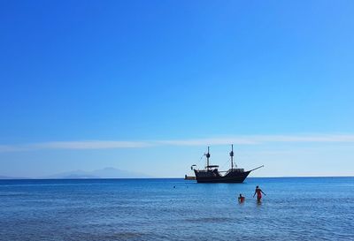 Boat sailing in sea against clear blue sky