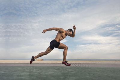 Full length of man jumping on beach against sky