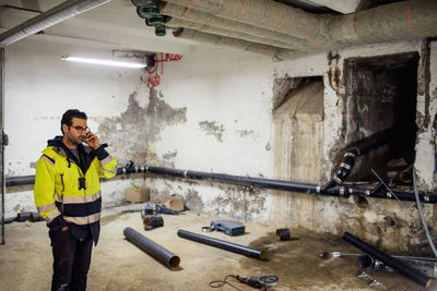 Man in protective clothing talking on phone in basement