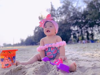 Full length of cute girl sitting on beach