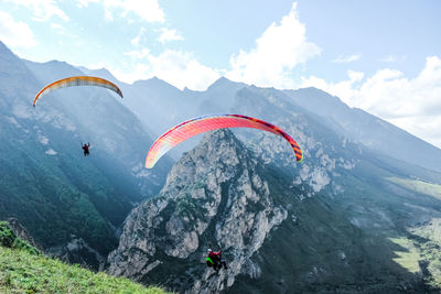 People paragliding on mountain peak against sky