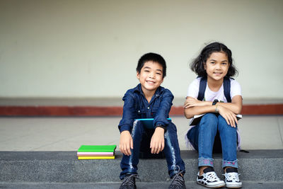 Portrait of smiling siblings sitting on staircase