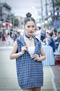 Portrait of young woman standing against blurred background