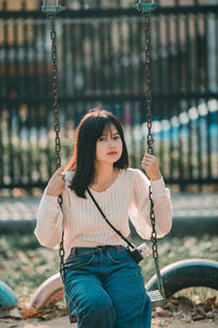 Young woman standing on swing at playground