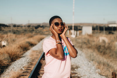 Portrait of young woman in sunglasses standing on railroad track