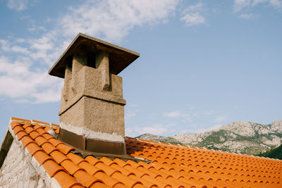 Low angle view of cross on roof of building against sky