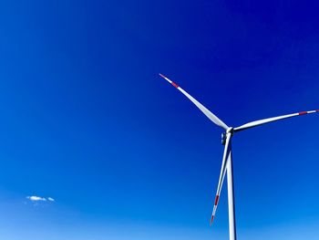 Low angle view of windmill against blue sky