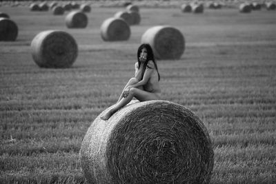 Woman with hay bales on field
