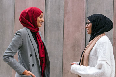 Young couple standing against wall in city