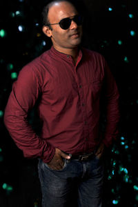 Young man wearing sunglasses standing at night