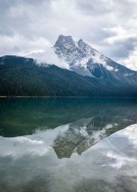 Mountain shrouded with clouds reflected in still waters of a lake, emerald lake, yoho np, bc, canada