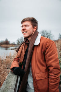 Young man looking away while standing by railing