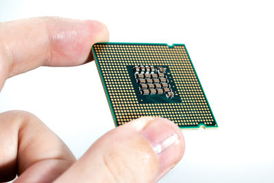 Close-up of hand holding camera over white background