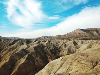 Scenic view of mountains against cloudy blue sky on sunny day