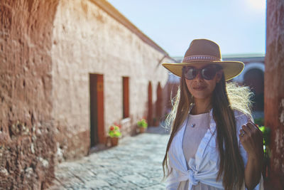 Portrait of smiling young woman standing against old building