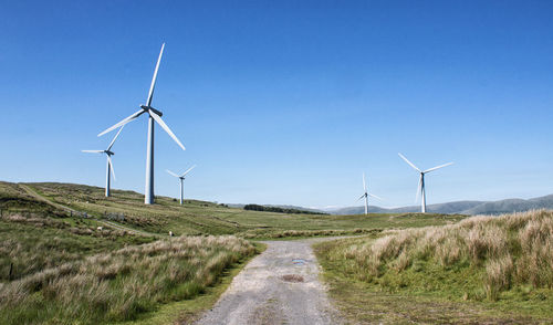 Wind turbines on field against clear sky