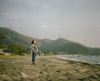 Full length of man standing on beach against sky