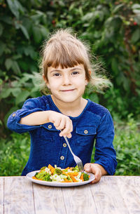 Portrait of girl eating food on table