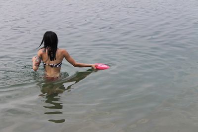 Rear view of woman swimming in sea