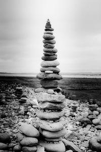 Stack of stones on beach against sky