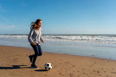 Rear view of woman standing at beach against sky