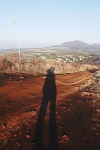 Shadow of man on field against clear sky