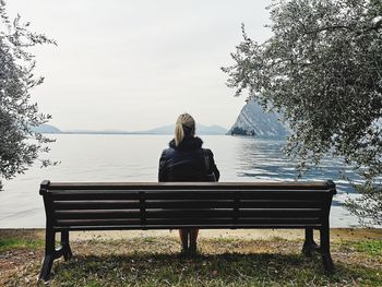 Rear view of woman sitting on bench in park