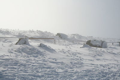 Snow covered land against clear sky