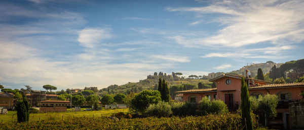Houses by trees and buildings against sky