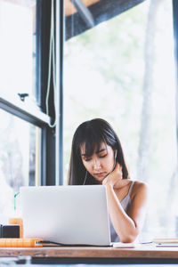 Young woman using phone while sitting on table