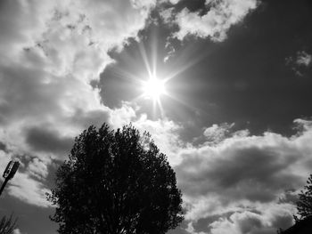 Low angle view of sun shining through clouds