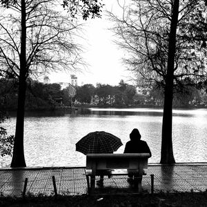 People sitting on bench by lake