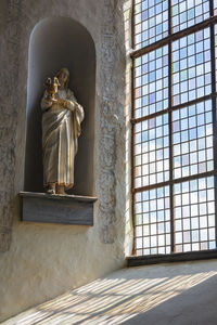 Statue against window in building