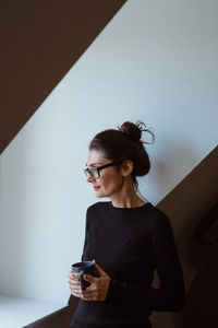 Young woman using mobile phone against wall